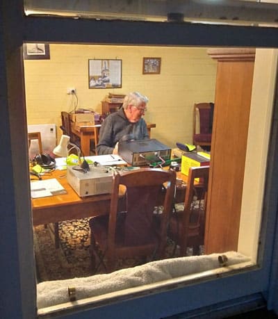 Bill ZL3VZ sitting at a rig, seen through a window of the light keepers quarters at Cape Campbell