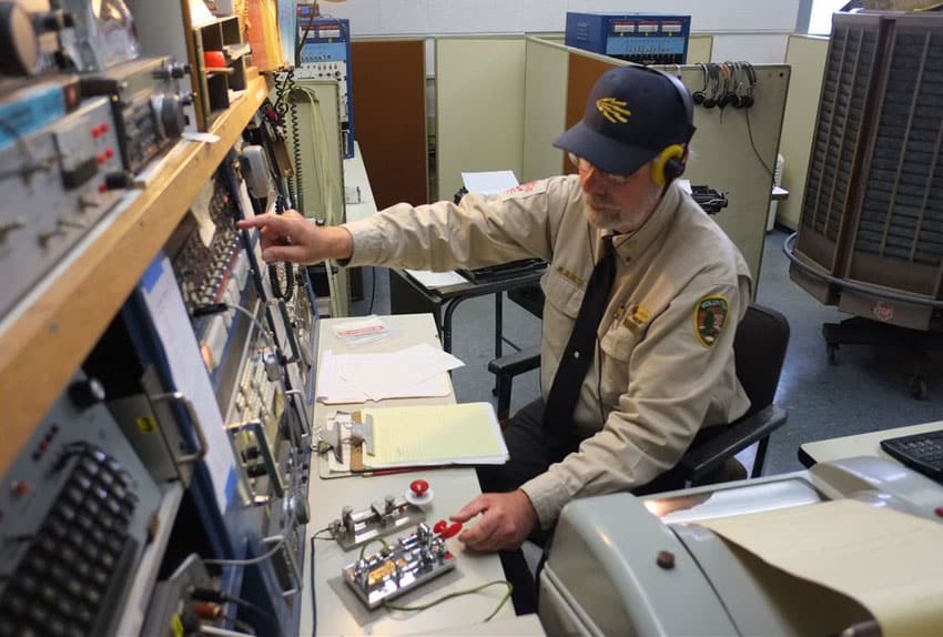 An operator sending Morse using a right-handed Vibroplex bug with his left hand at the restored KPH
