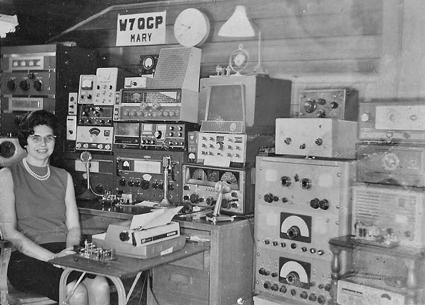 Mary W7QGP sitting at typewriter with Vibroplex Lightning bug in shack filled with 1950s ham gear