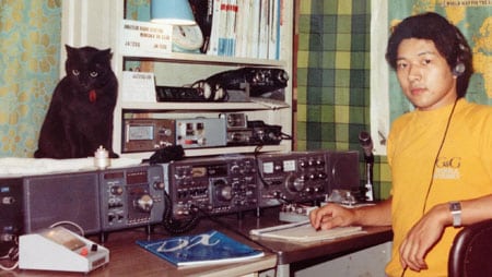 Cat sitting on shelf in ham shack with ham operator