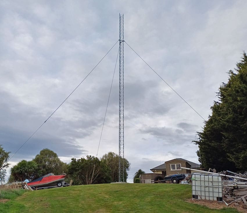 The tower standing with its 3 guys, house in background