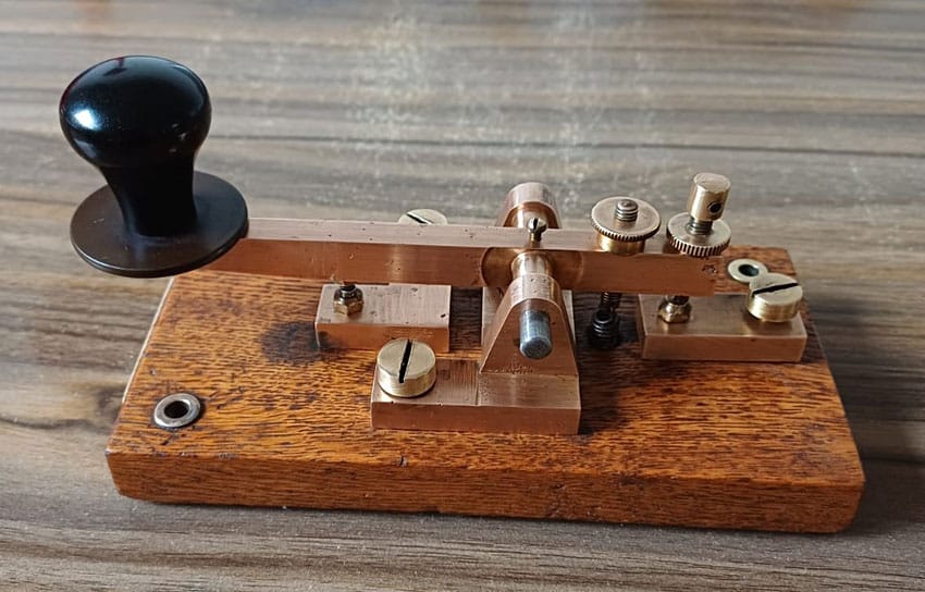 Old telegraph key, brass on oak, labelled A and W McCarthy