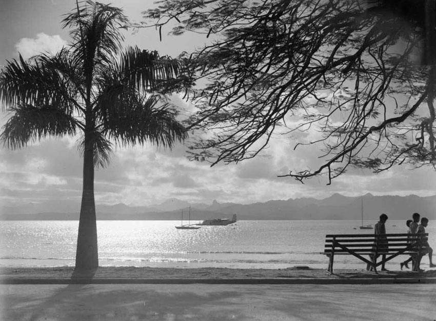 harbour scene with schooner and flying boat at anchor, palm tree and children in foreground